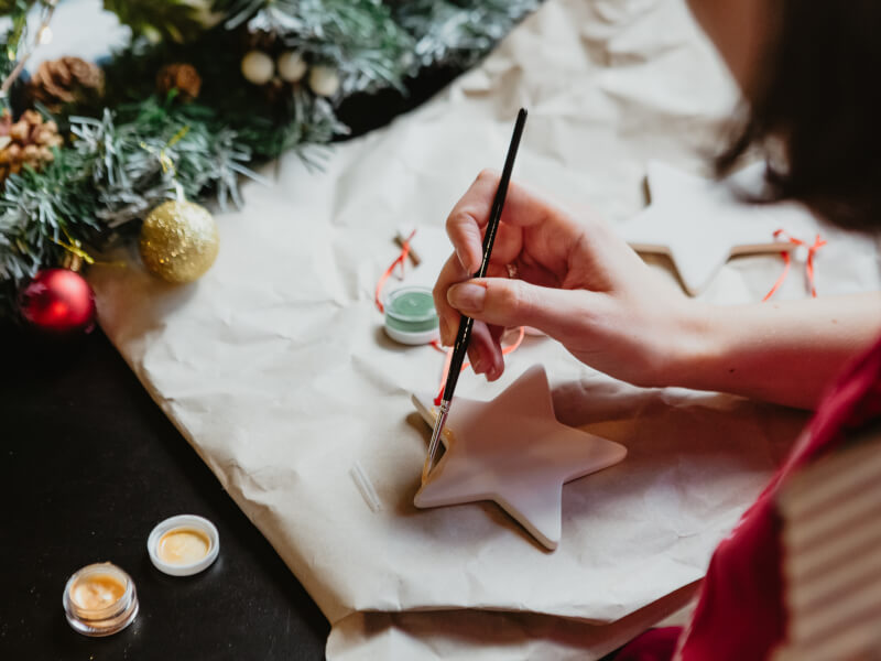 Close up of a person painting a ceramic Christmas ornament